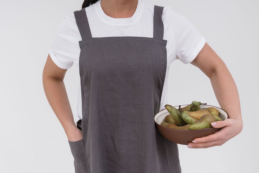 12. Woman in grey Japanese-style linen apron holding bowl of pears, shown from waist up