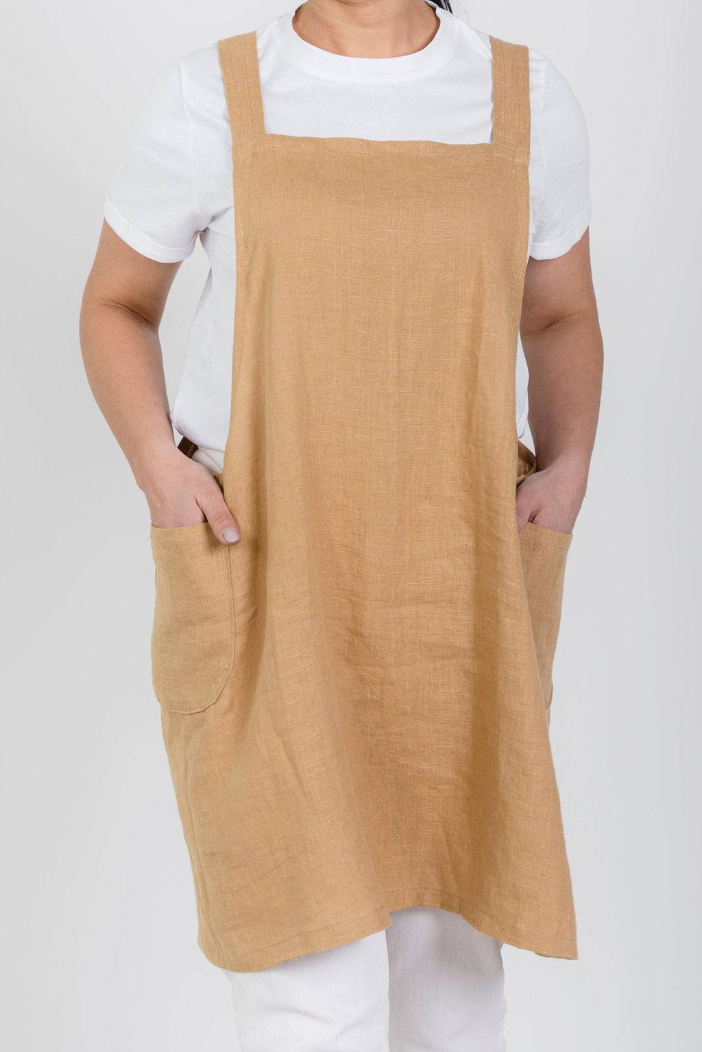 9. Front view of woman wearing beige Japanese-style linen apron with pockets over white shirt