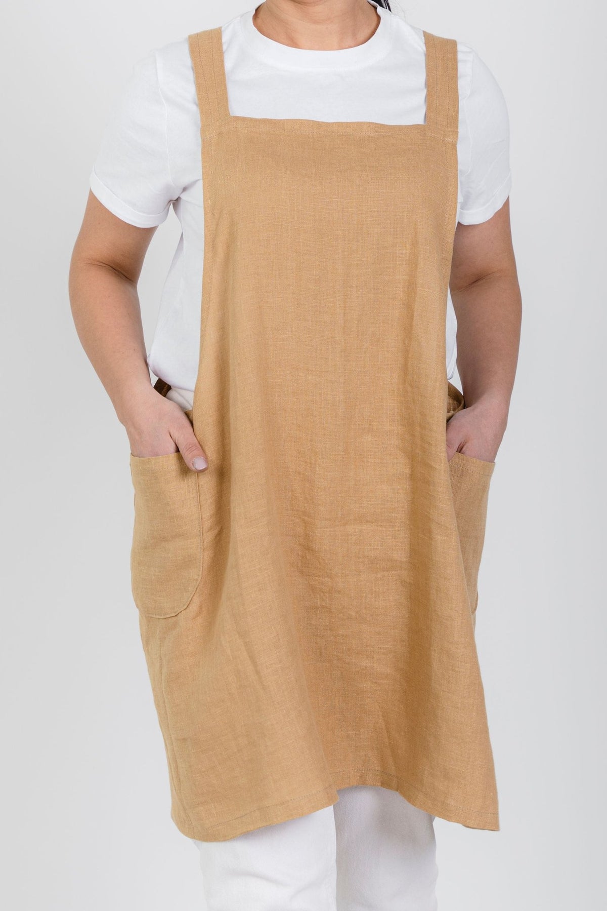 9. Front view of woman wearing beige Japanese-style linen apron with pockets over white shirt