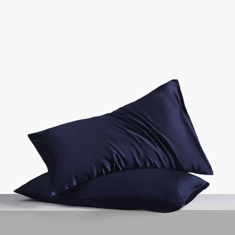 2. Pair of navy blue silk pillowcases on light grey surface, highlighting smooth fabric