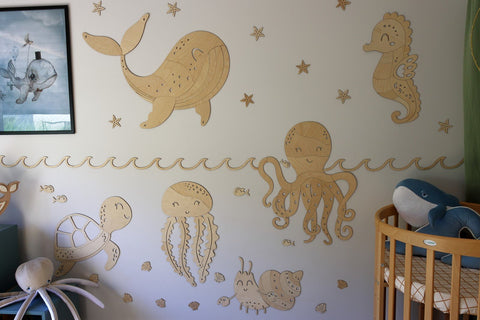3. Ocean-themed nursery with wooden jellyfish, octopus, and whale wall decorations