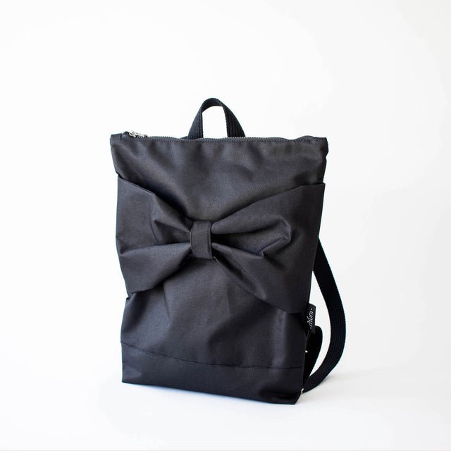 6. Studio image of Muni Black Bow waterproof backpack, featuring large bow and sturdy polyester material