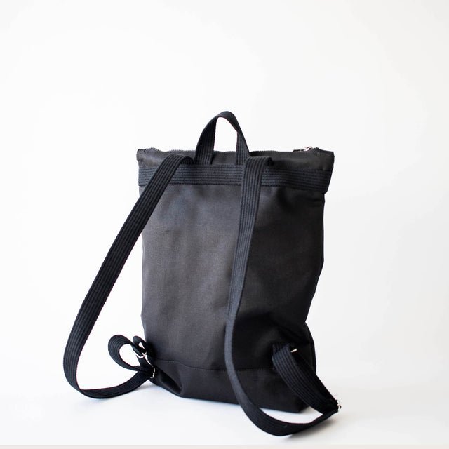 9. Back view of Muni Black Bow backpack in studio, showing adjustable shoulder straps and durable design