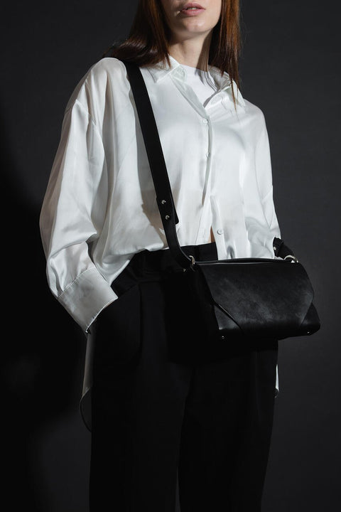 4. Woman wearing black leather Stella Soomlais shoulder bag over white shirt and black pants in studio setting