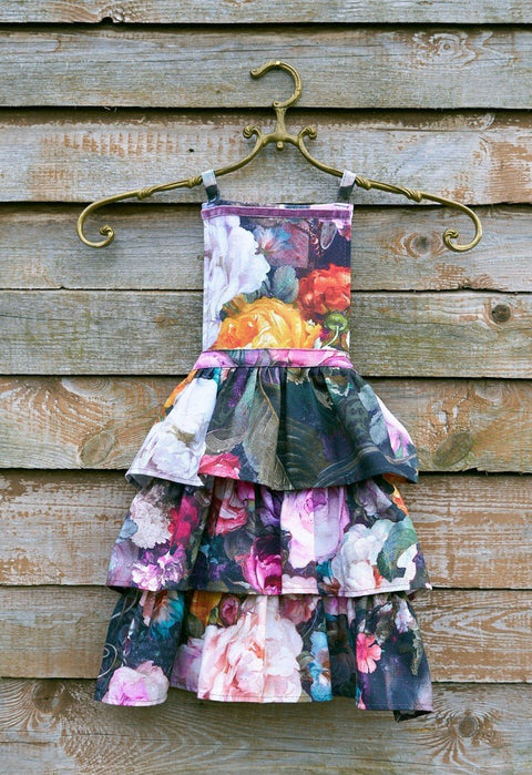 2. Hortensias Home Francine Black kids apron with dark floral print hanging on a wooden wall, showcasing layered design