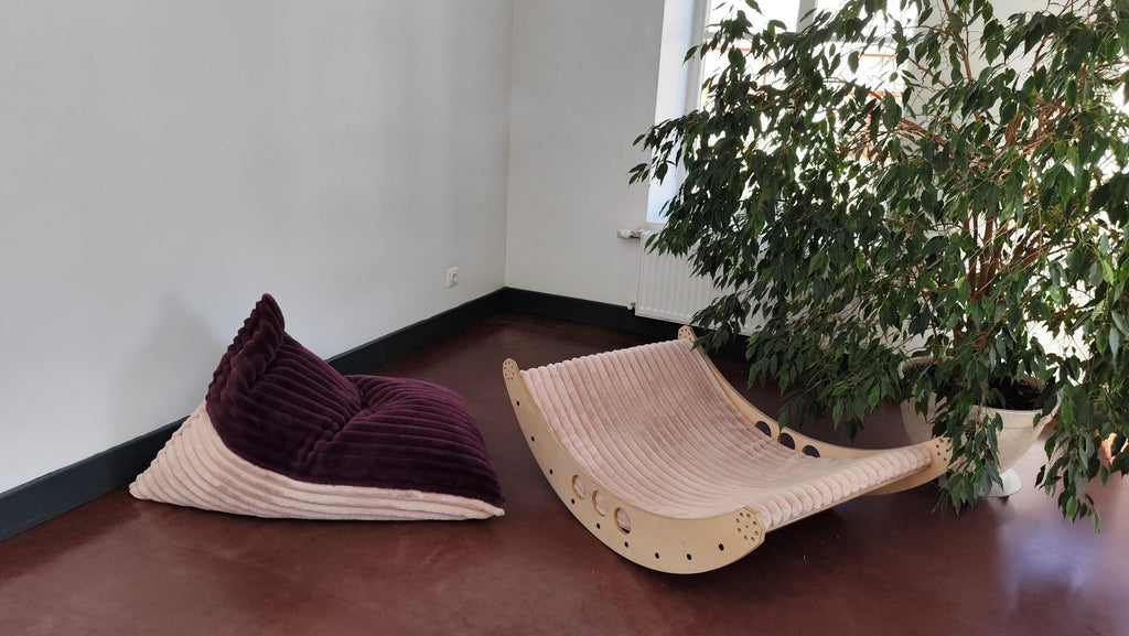2. Luula kids bean bag chair in berry and rose mousse tones beside a wooden lounger, in a minimalist room with a large plant