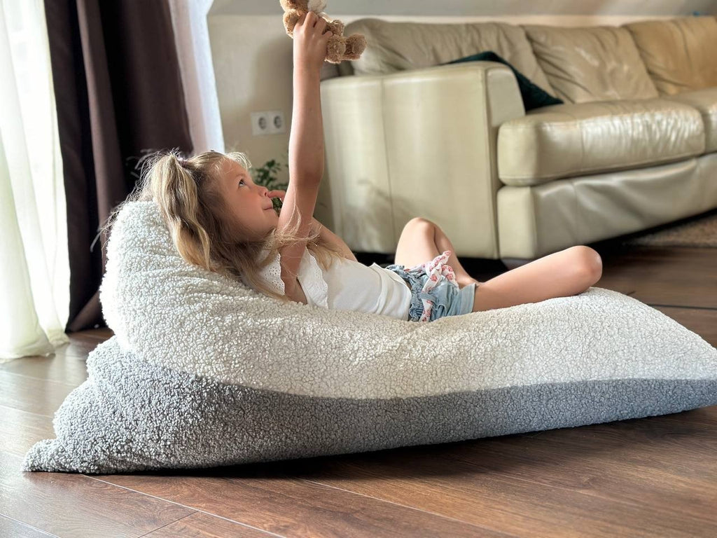 1. Girl playing with toy on Luula Kids Bean Bag Chair in two-tone sherpa, in a living room