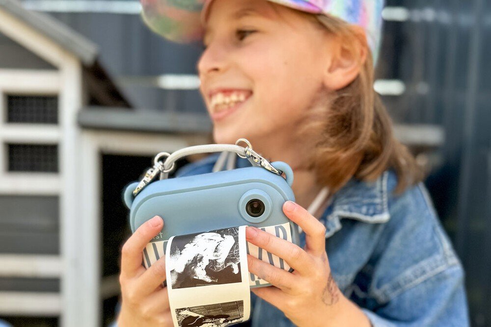 1. Child smiling while using blue Hoppstar camera outdoors