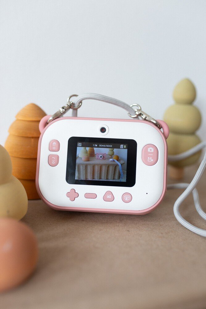 3. Back view of pink Hoppstar camera showing screen and buttons on wooden surface with toys