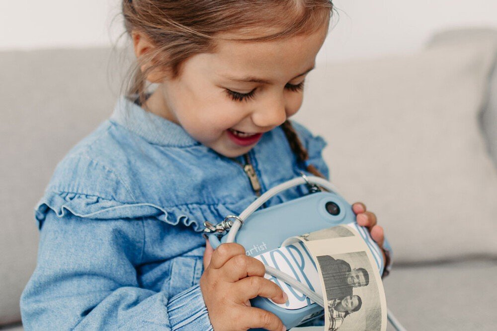 1. Child smiling while using blue Hoppstar camera outdoors