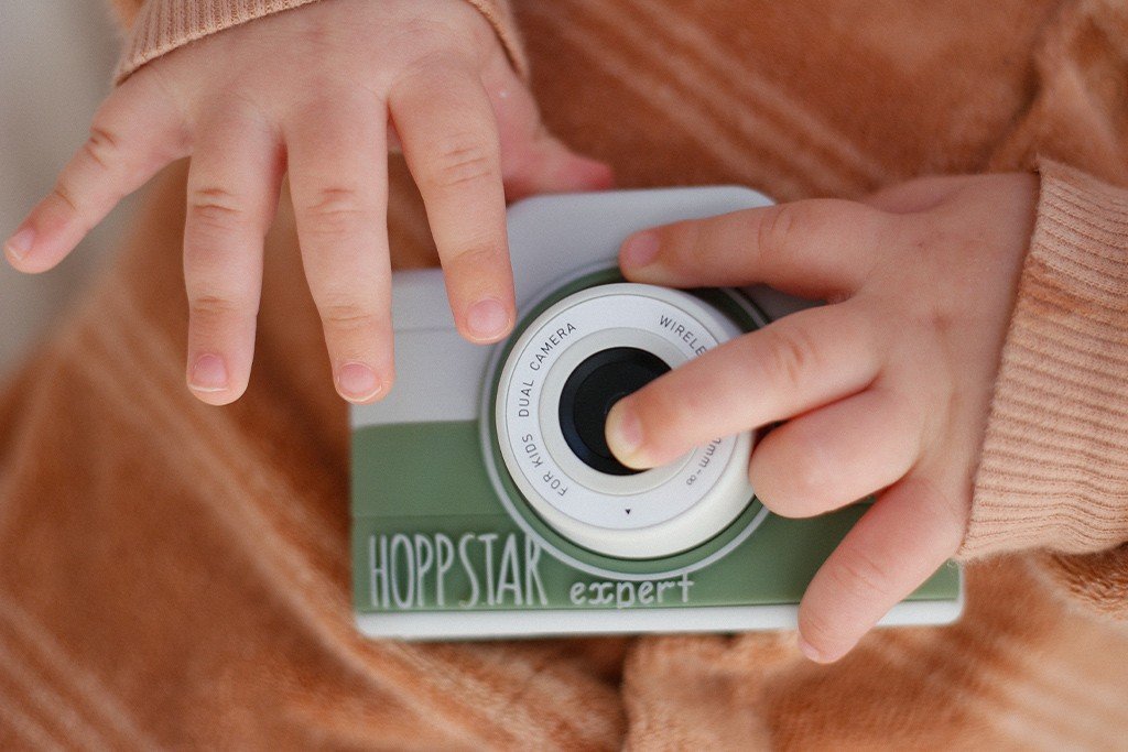 1. Child holding green Hoppstar Expert camera, close-up of hands