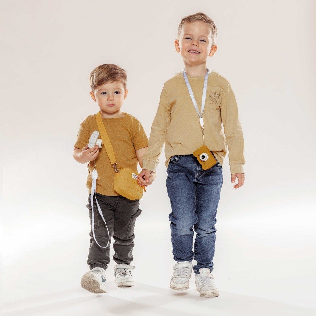 1. Two boys holding yellow Hoppstar Expert cameras, wearing casual outfits in studio setting