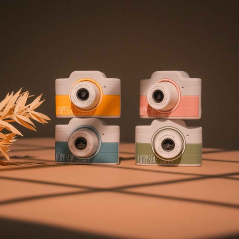 1. Four Hoppstar Expert cameras in different colors stacked on wooden surface, warm lighting