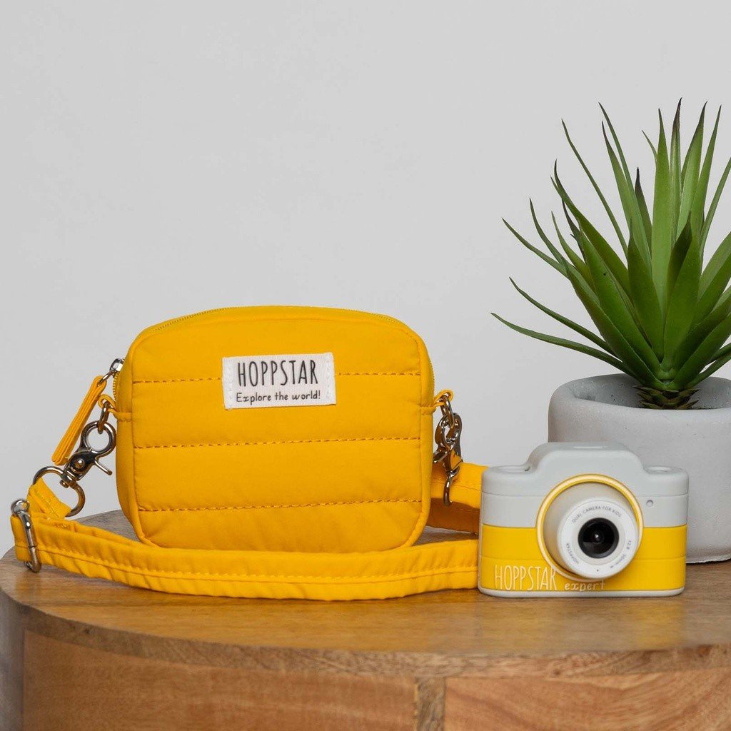 1. Yellow Hoppstar Expert camera with matching bag on wooden table, plant in background