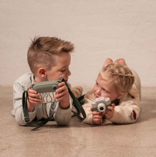 1. Two children lying on floor with Hoppstar Expert cameras, smiling