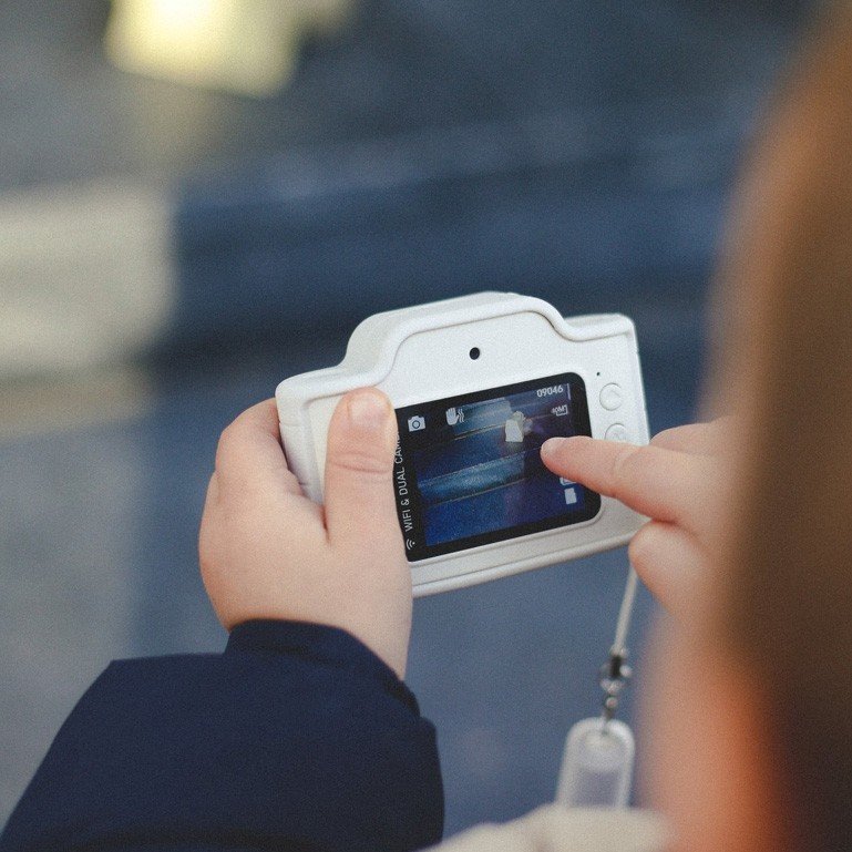 1. Child using white Hoppstar Expert camera outdoors, focusing on screen