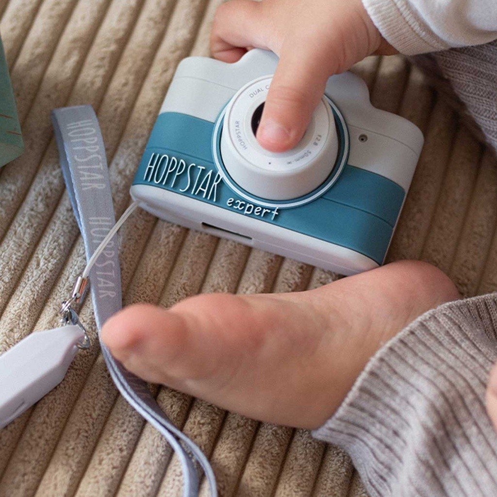 1. Child holding blue Hoppstar Expert camera, close-up of hands and feet