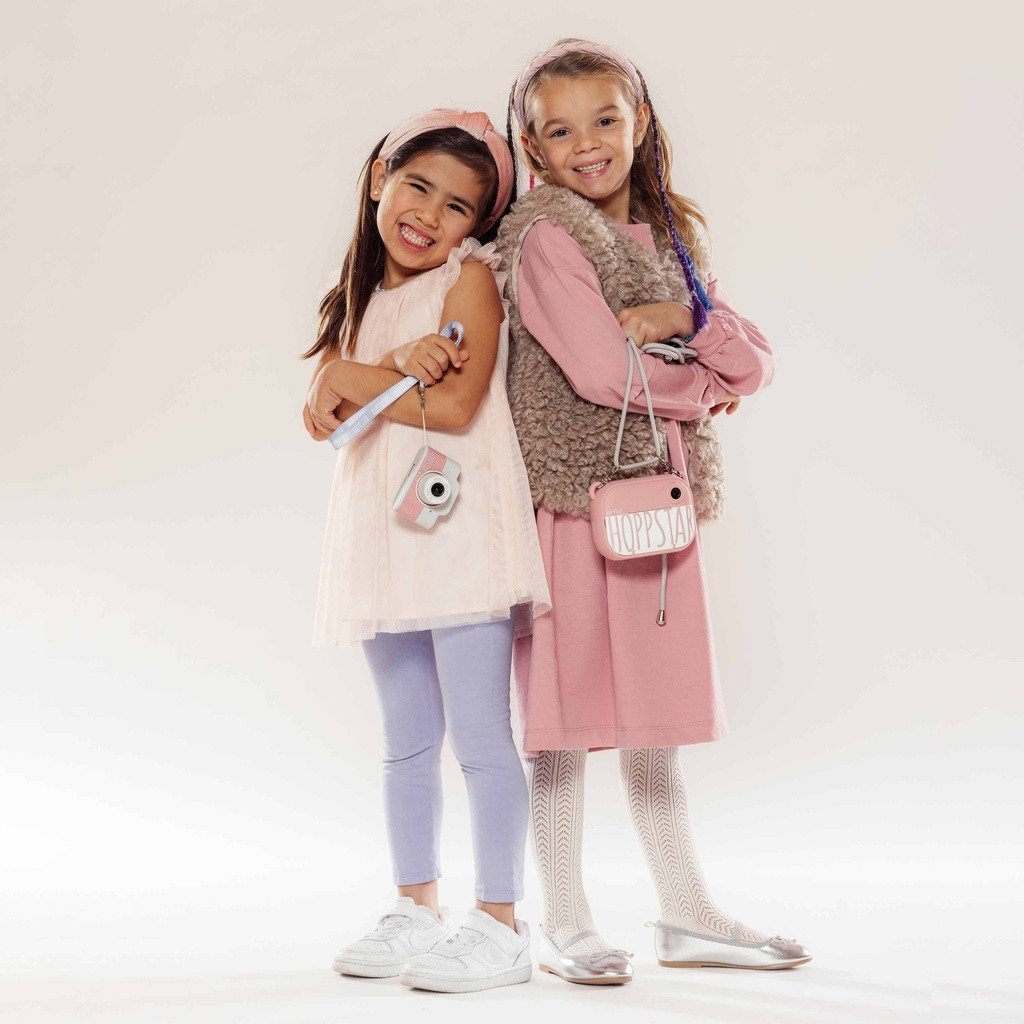 1. Two girls posing with Hoppstar Expert cameras, wearing casual outfits in studio setting