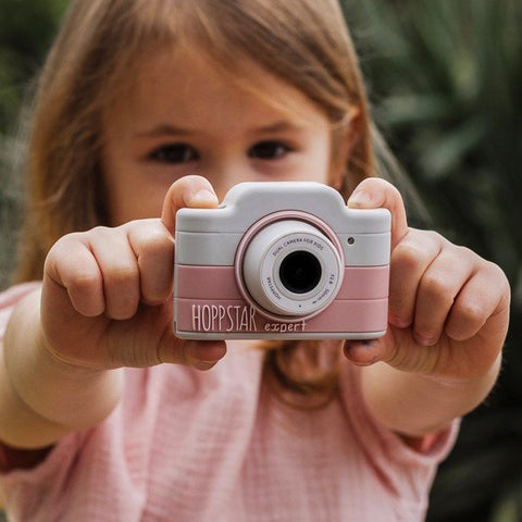 1. Girl holding pink Hoppstar Expert children's camera outdoors, smiling