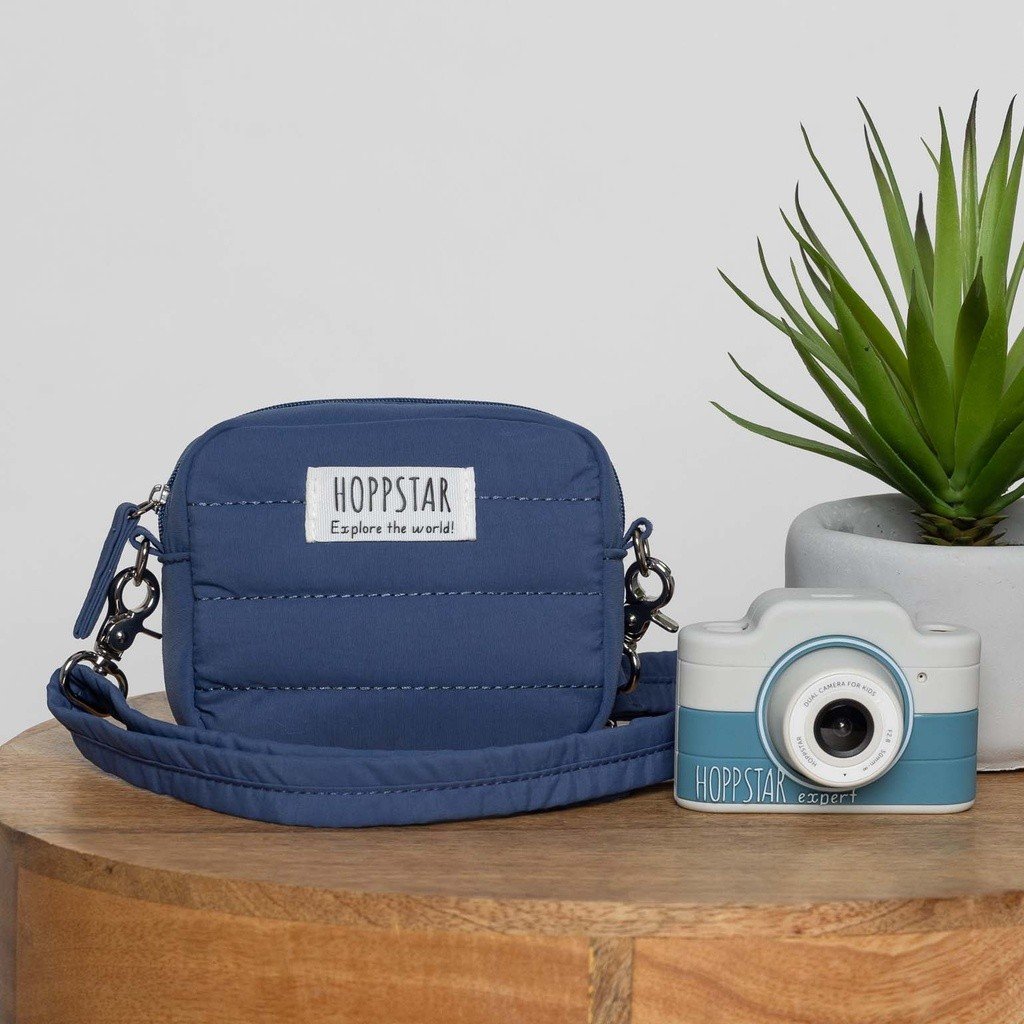 1. Blue Hoppstar Expert camera with matching bag on wooden table, plant in background