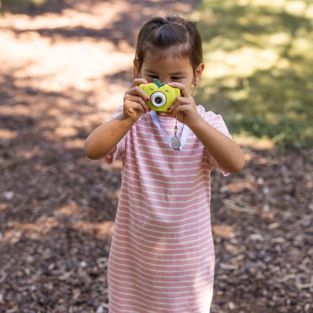 1. Girl in striped dress using green Hoppstar Rookie camera in park setting