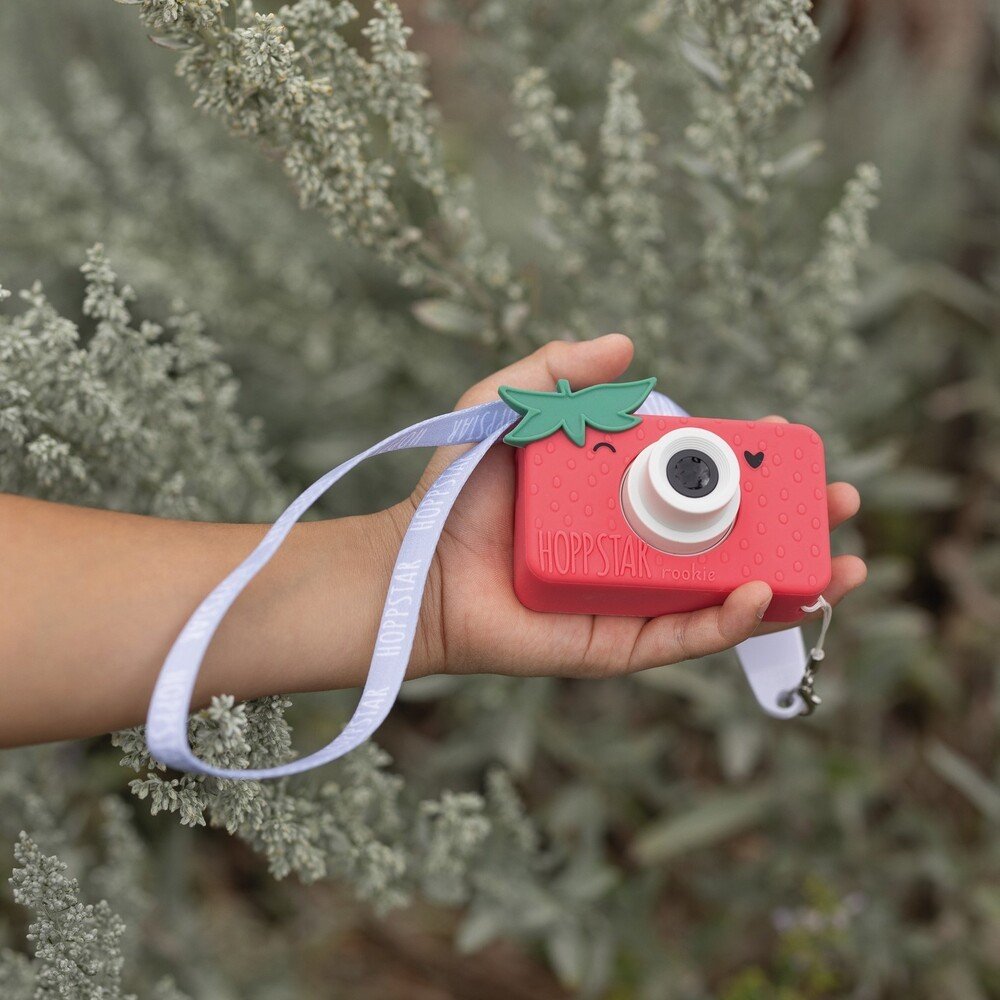 1. Child holding pink Hoppstar Rookie camera with lanyard in natural setting