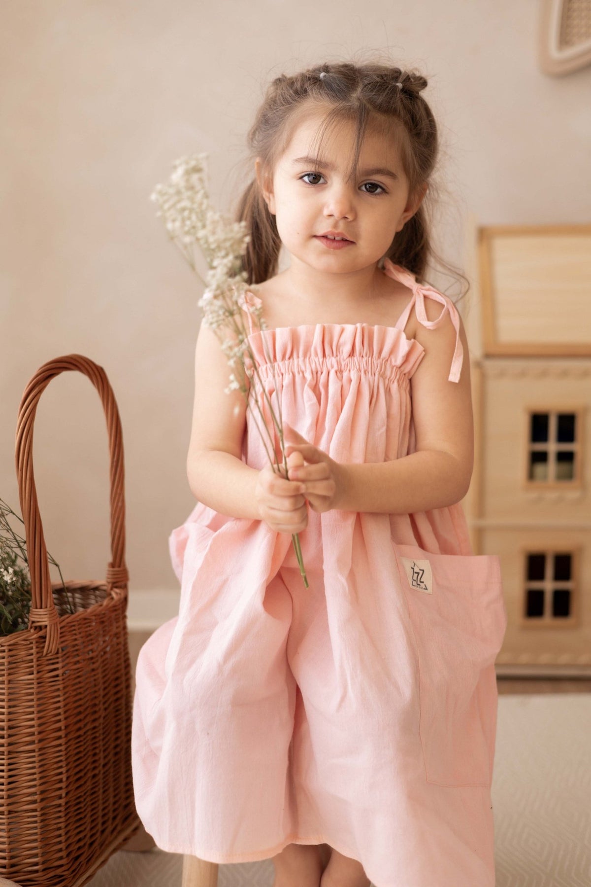 3. Girl holding flowers wearing peach dress with adjustable shoulder ties indoors