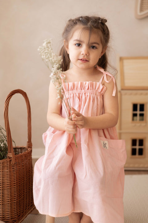 3. Girl holding flowers wearing peach dress with adjustable shoulder ties indoors