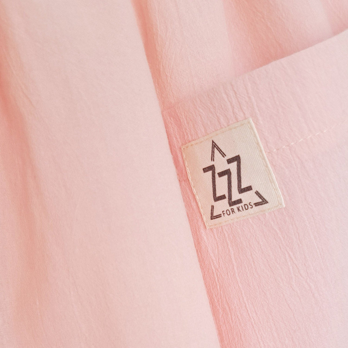 6. Close-up of Zezuzulla logo on peach cotton fabric of kids dress