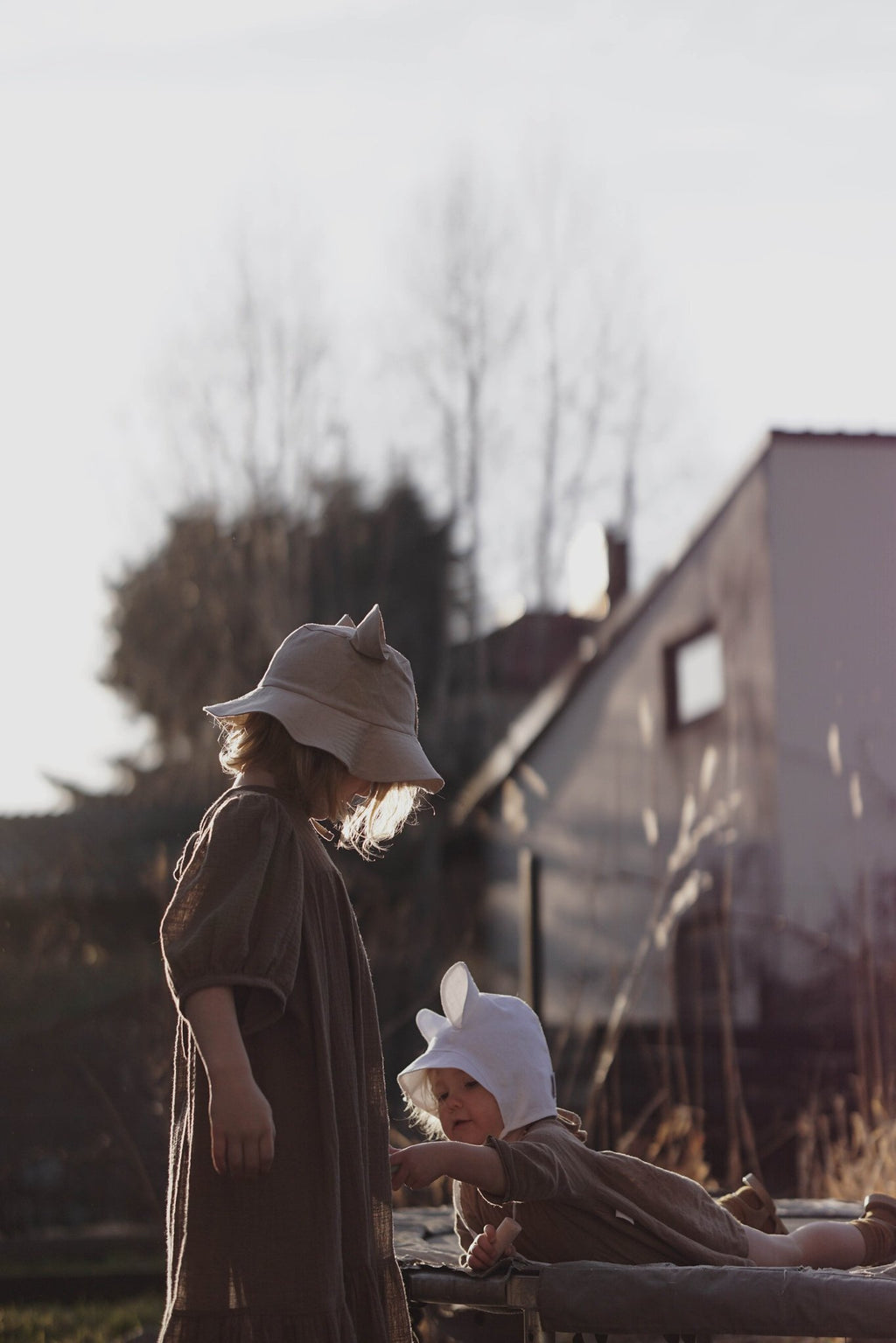 3. Two children wearing beige and white hats with ears playing outdoors