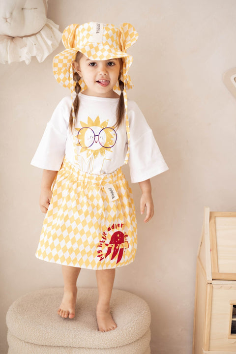 4. Child standing on stool wearing yellow and white checkered hat with ears and matching outfit