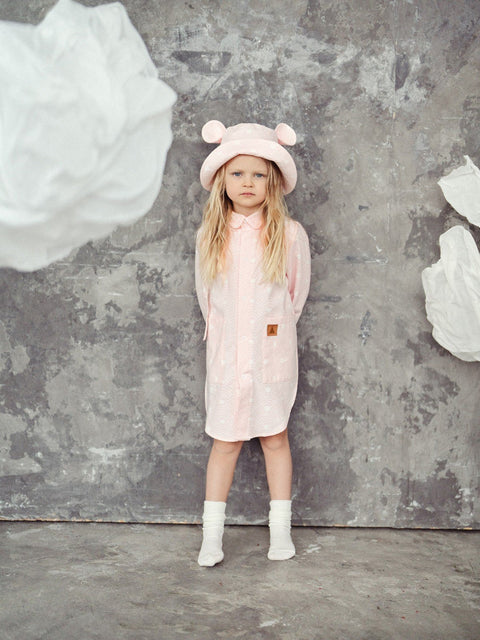 2. Full view of child in pink hat with ears and matching outfit, standing in artistic setting