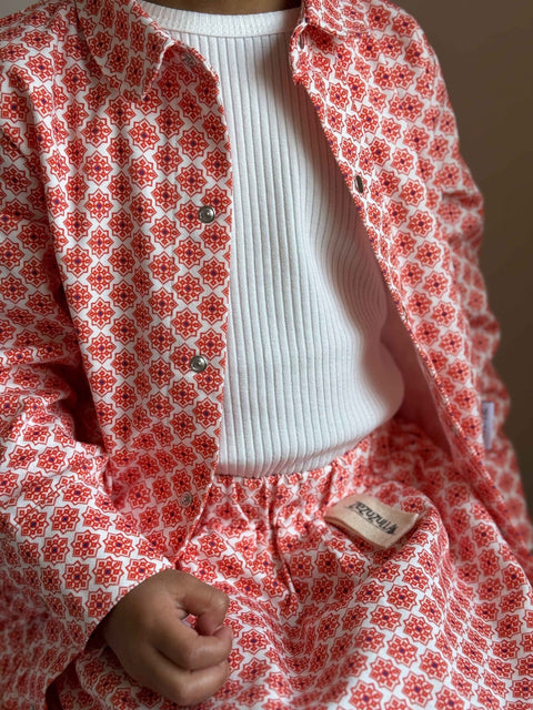 3. Close-up of Zezuzulla red patterned jacket and skirt with white ribbed top, highlighting fabric texture and button details