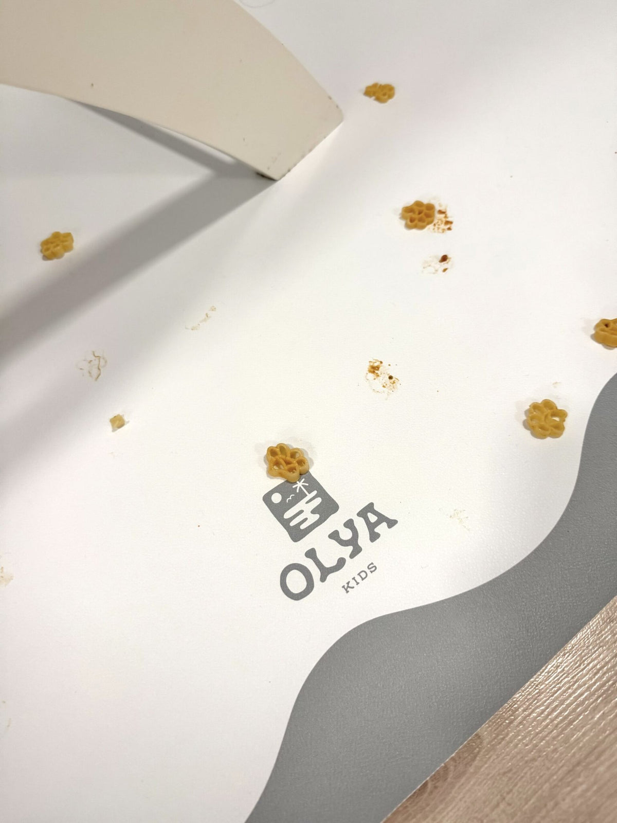 3. Close-up of OLYA KIDS floor mat with food spills, showcasing non-slip waterproof surface and brand logo