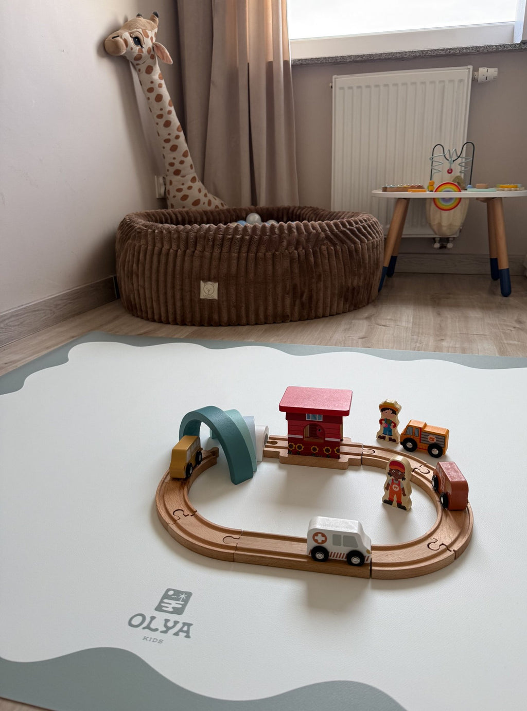 1. Children's room with OLYA KIDS floor mat, toy train set, and plush giraffe, soft natural light