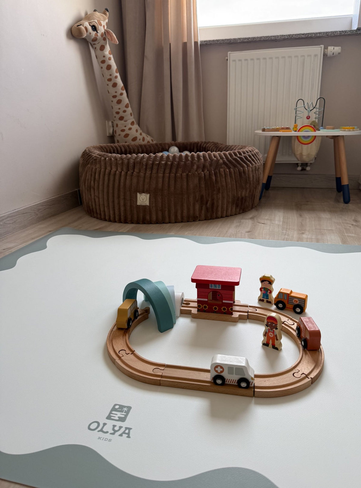 1. Children's room with OLYA KIDS floor mat, toy train set, and plush giraffe, soft natural light