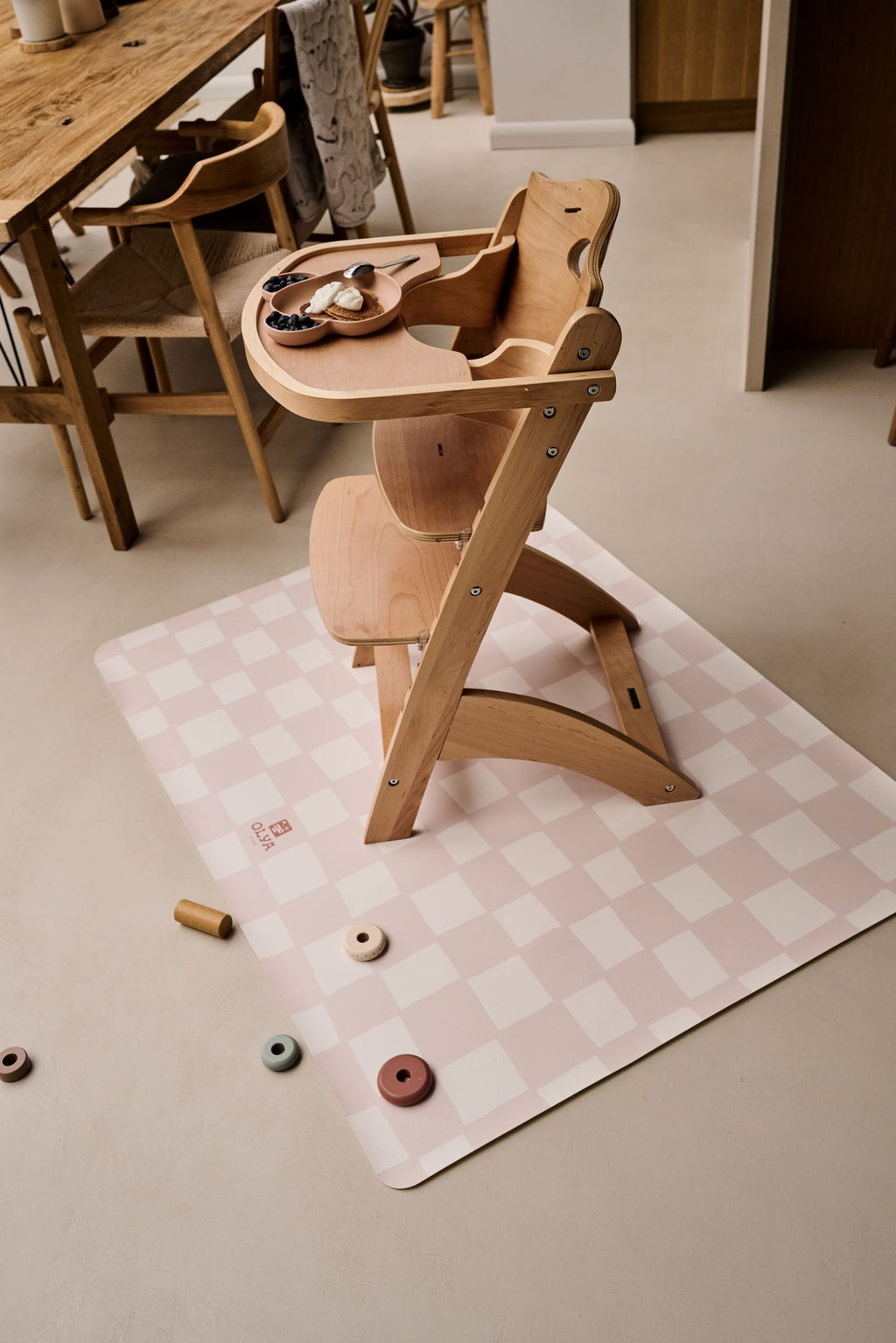 1. Wooden high chair on pink and beige checkered OLYA KIDS floor mat in dining room setting