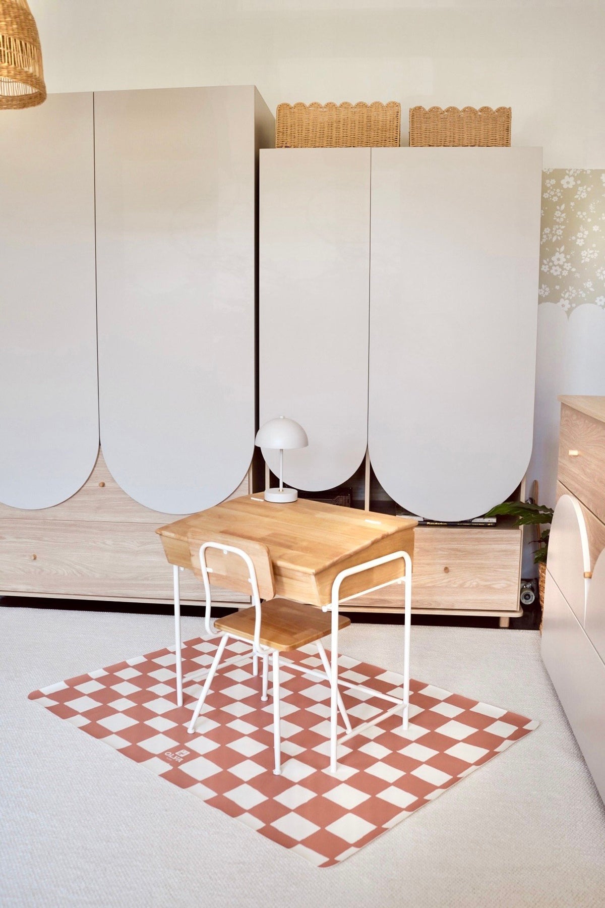 4. Pink and beige checkered floor mat under a wooden desk and chair in a bright room