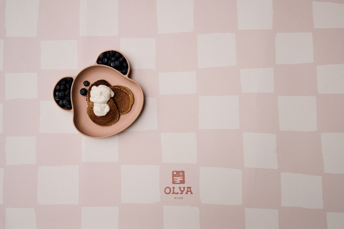 2. Close-up of pink and beige checkered OLYA KIDS floor mat with bear-shaped plate and food