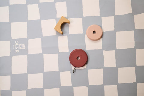 3. Close-up of OLYA KIDS logo on blue and white checkered vegan leather floor mat with toy pieces