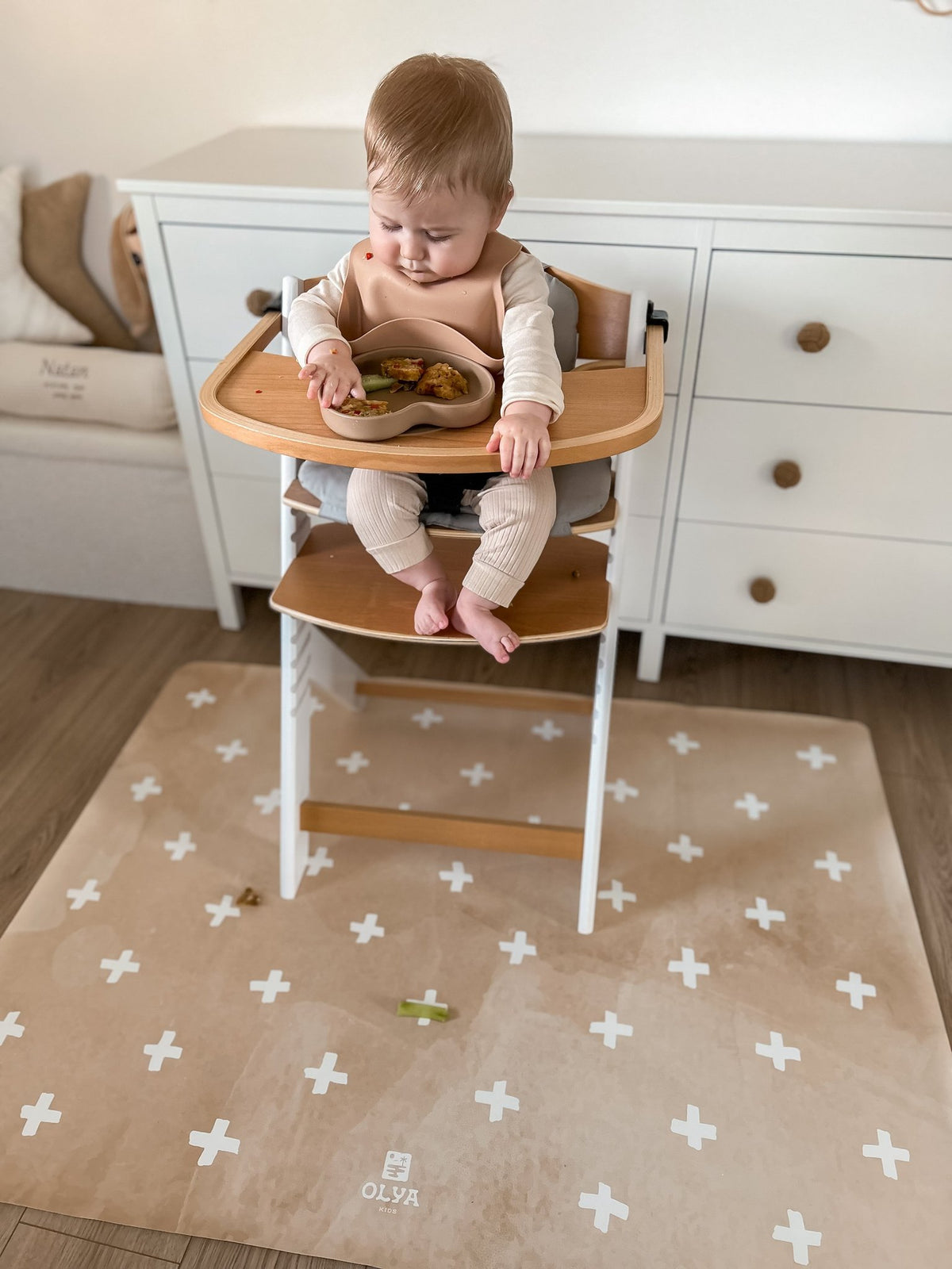 8. Baby in high chair on beige OLYA KIDS floor mat with cross pattern, eating from bowl, in cozy home