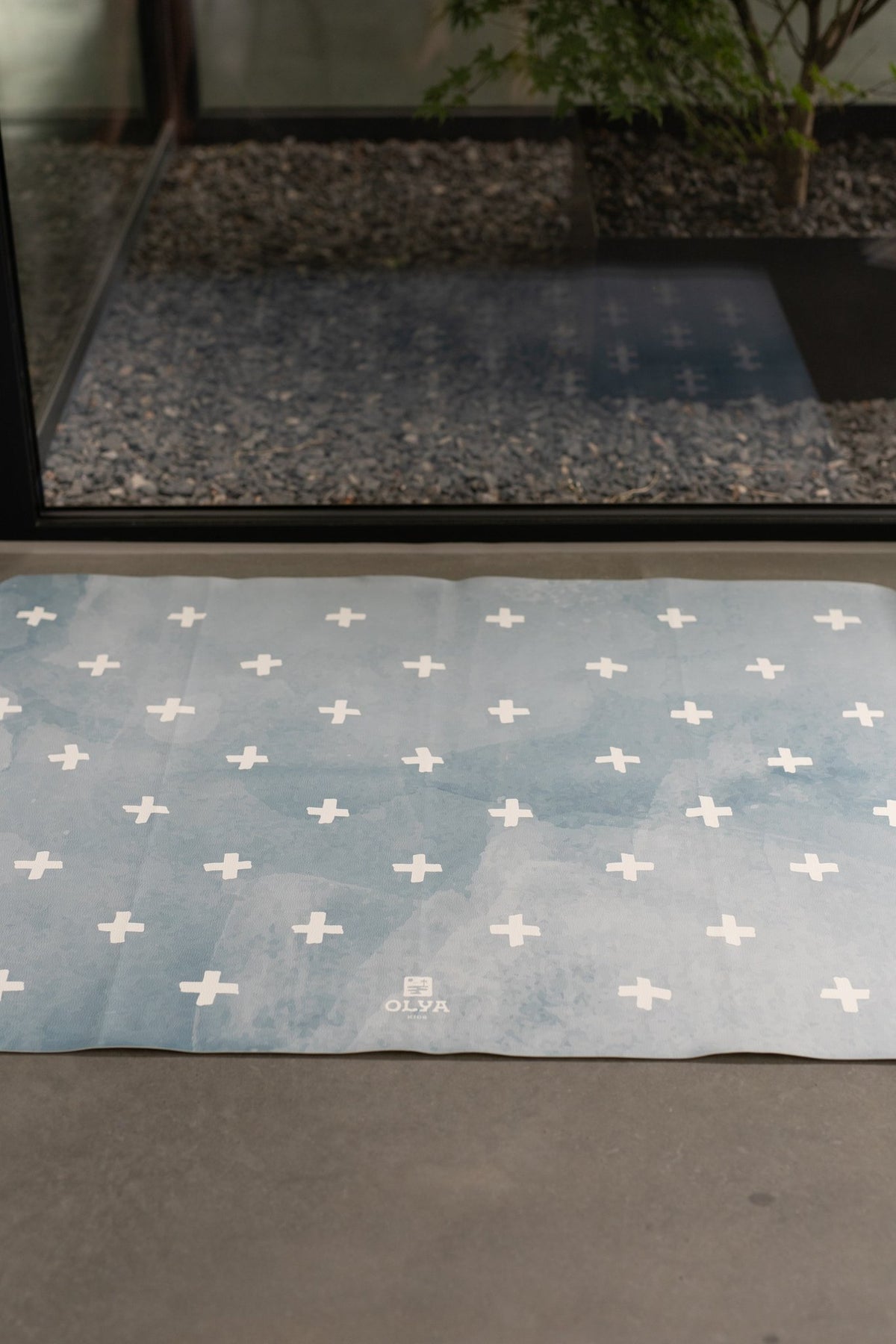 2. Blue OLYA KIDS floor mat with white cross pattern laid flat on concrete floor