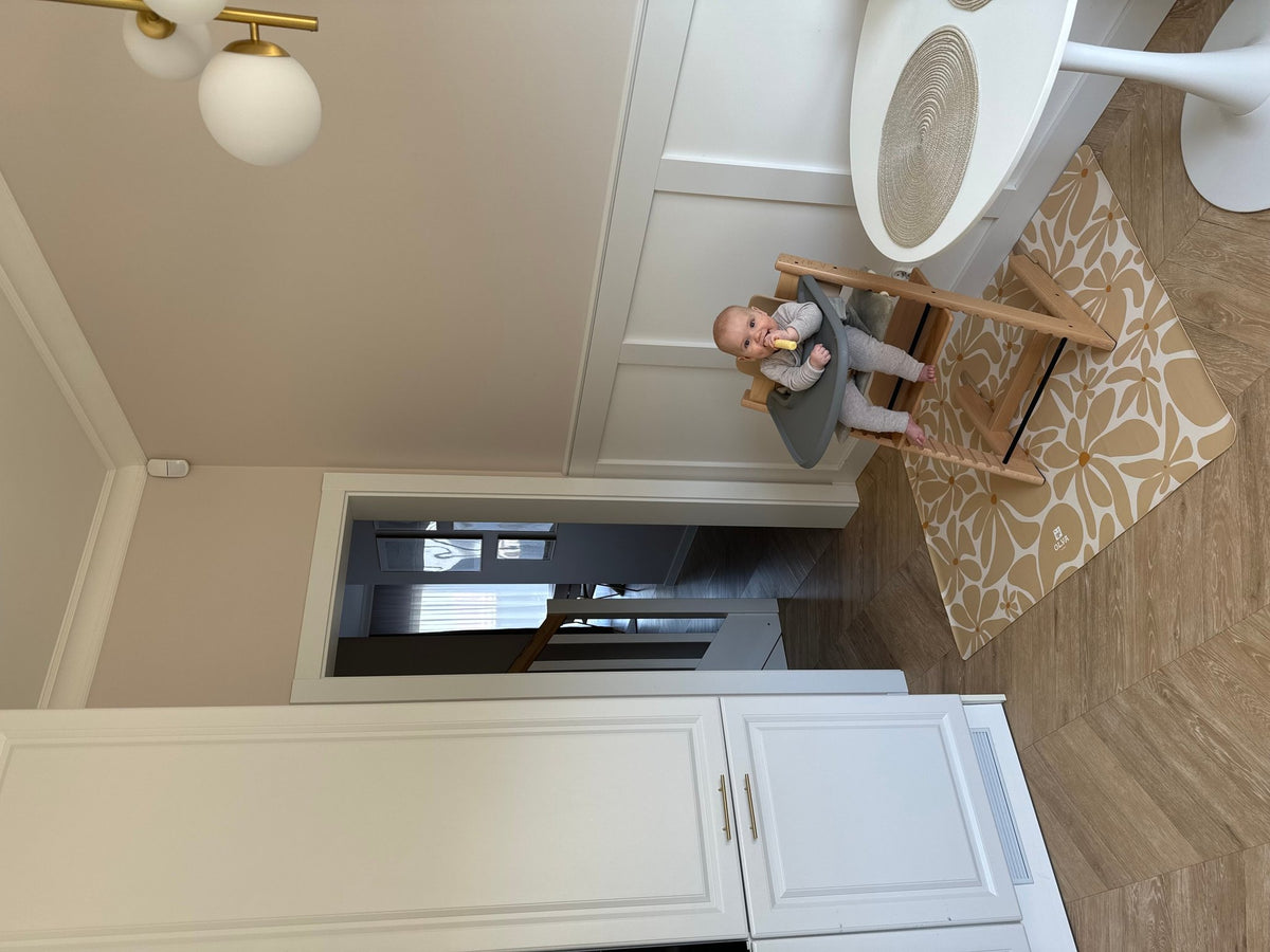 1. Baby in high chair on beige daisy-patterned OLYA KIDS floor mat in kitchen