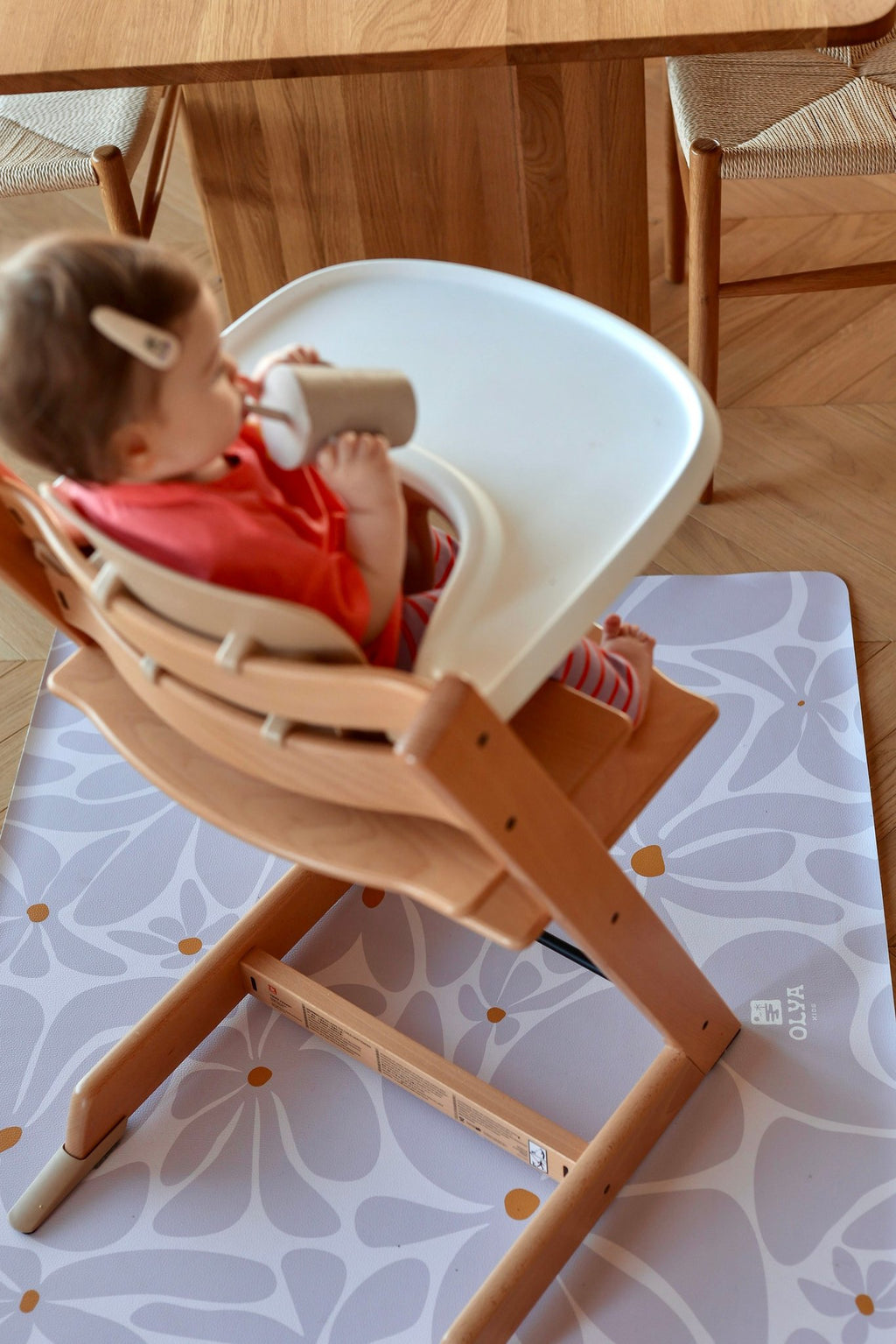 10. Baby in high chair on lavender daisy-patterned floor mat in dining area