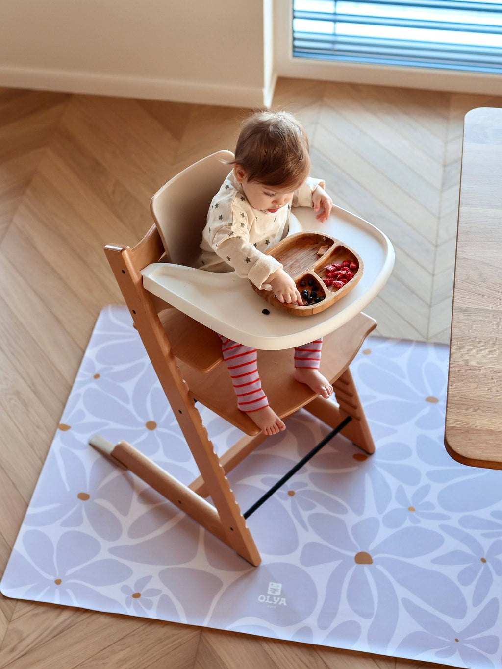 4. Baby in high chair on lavender daisy-patterned floor mat in dining room