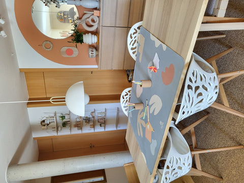 2. Kids' mealtime floor mat in organic sea design on dining table with two white chairs, featuring abstract shapes and OLYA KIDS logo