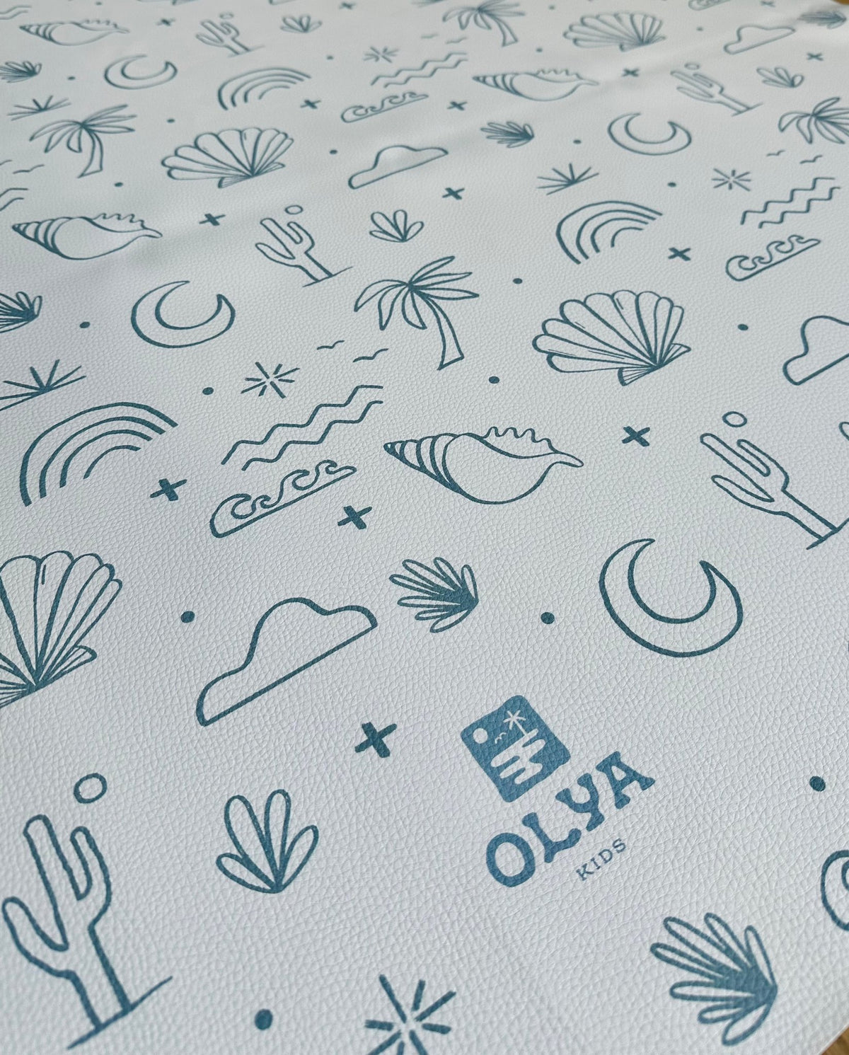 3. Close-up of OLYA KIDS floor mat showing palm trees, shells, and waves pattern