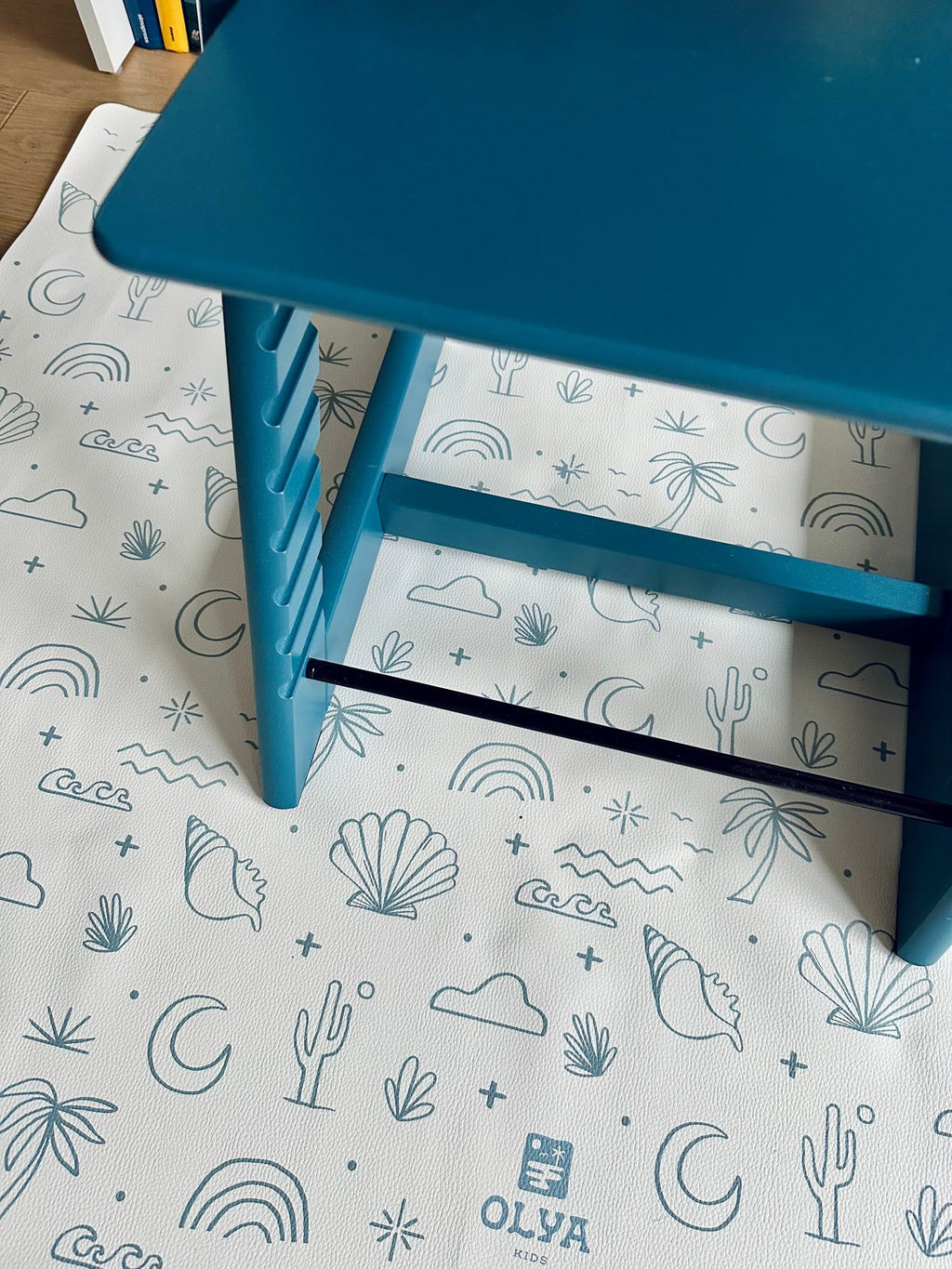 2. Blue high chair on OLYA KIDS Palm Beach Azure floor mat with beach-themed patterns