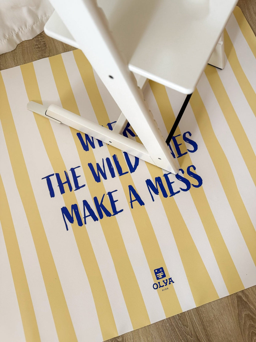 3. White high chair on yellow and white striped floor mat with text 'Where the wild ones make a mess', OLYA KIDS logo visible
