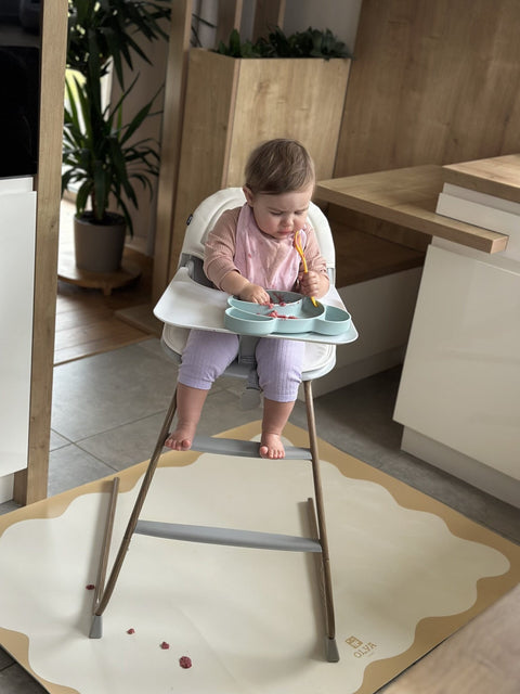 1. Child sitting in a high chair on a yellow-framed OLYA KIDS waterproof floor mat in a modern kitchen setting